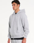 Model wearing grey zip up hoodie facing to the left