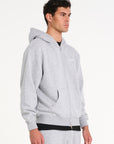 Model wearing grey zip up hoodie facing to the right