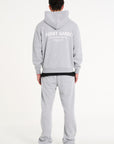 Backshot of model wearing full grey tracksuit with Avant Garde logo on the back