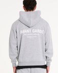 Backshot of model wearing grey zip up hoodie with Avant Garde writing across the back