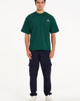 Model wearing green crew neck T-shirt with navy cargo pants