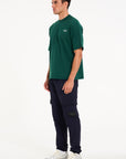 Side shot of model wearing green crew neck T-shirt with navy cargo pants