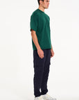 Model facing to the right wearing green crew neck T-shirt and navy cargo pants