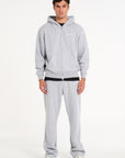 Model wearing full grey tracksuit with zip up hoodie and tracksuit bottoms
