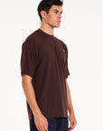 Model facing to the right wearing brown crew neck T-shirt