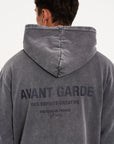 Model facing away from camera showing men's hoodie with Avant Garde writing on the back