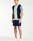 Side profile of model wearing block men's knitted polo in blue and shorts