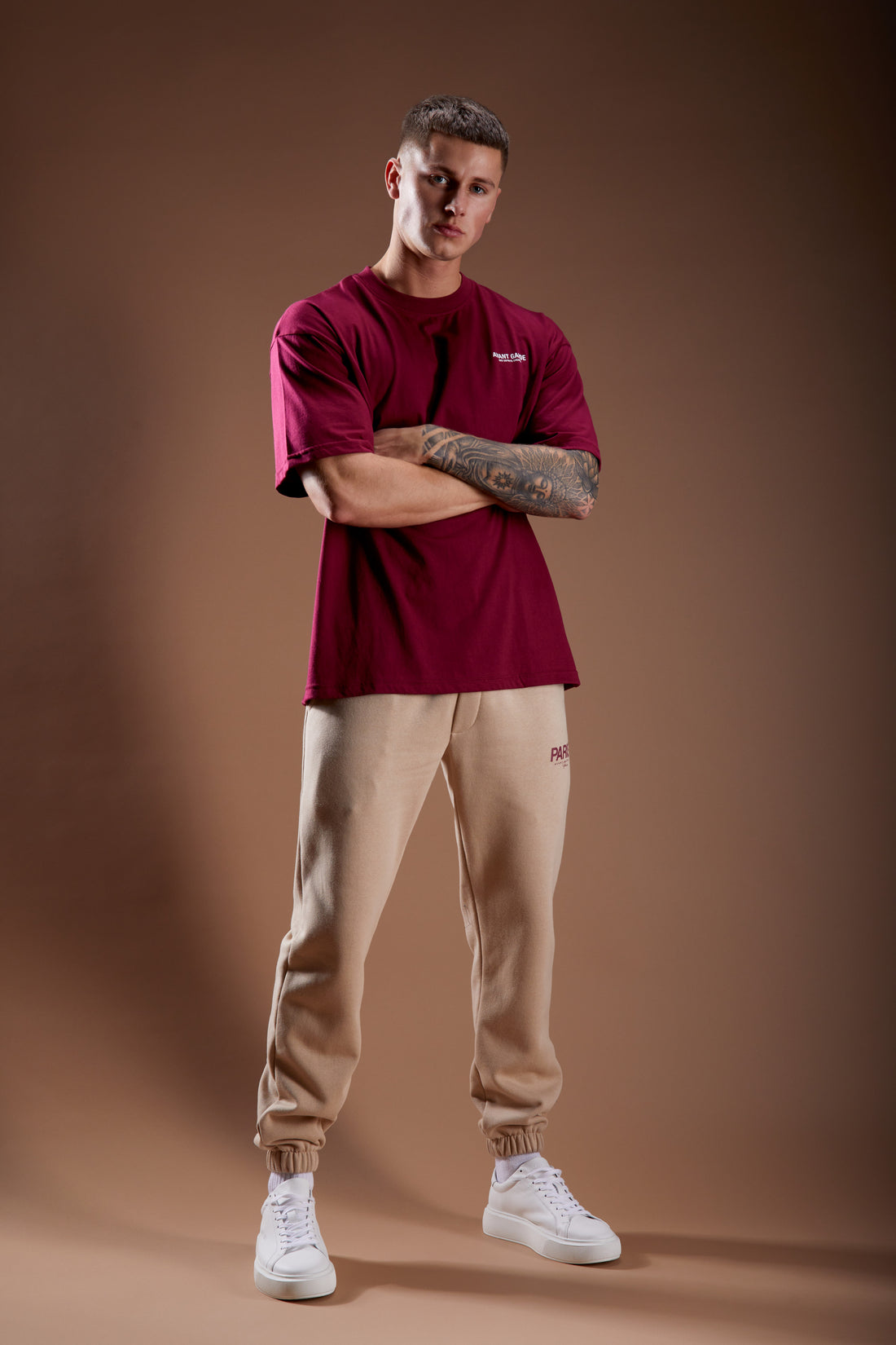 Model in beige joggers and burgundy logo t-shirt
