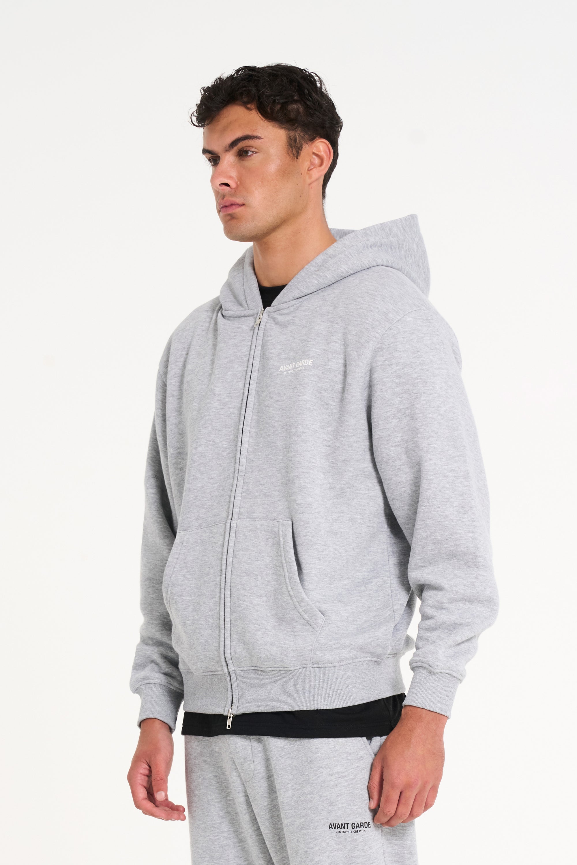 Model wearing grey zip up hoodie facing to the left