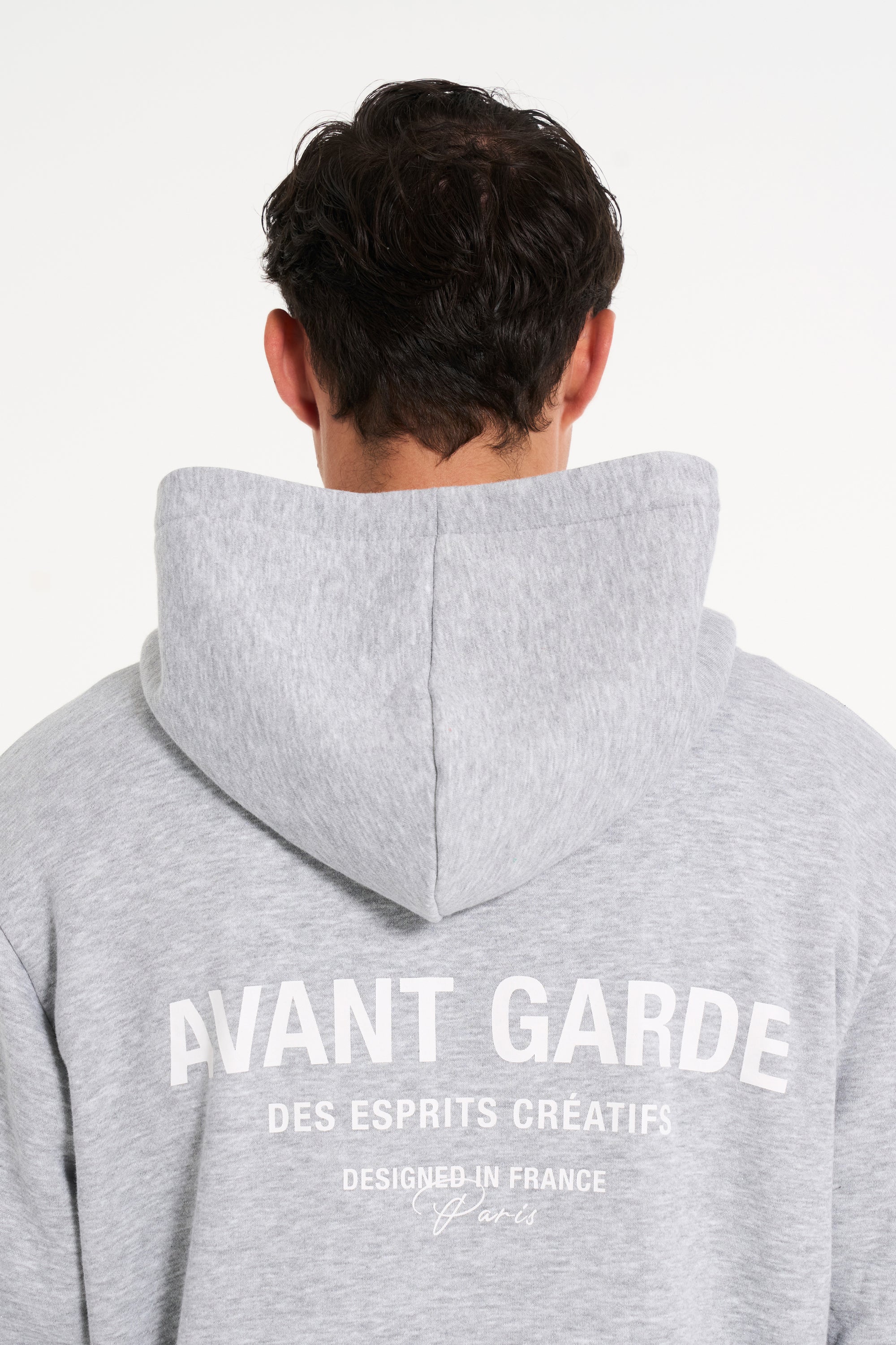 Close up backshot of model wearing grey hoodie with Avant Garde logo on the back