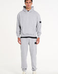 Model facing forward wearing full grey badge tracksuit