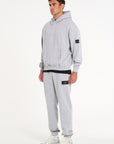 Model facing sidewards wearing grey full tracksuit with Avant Garde badge logo