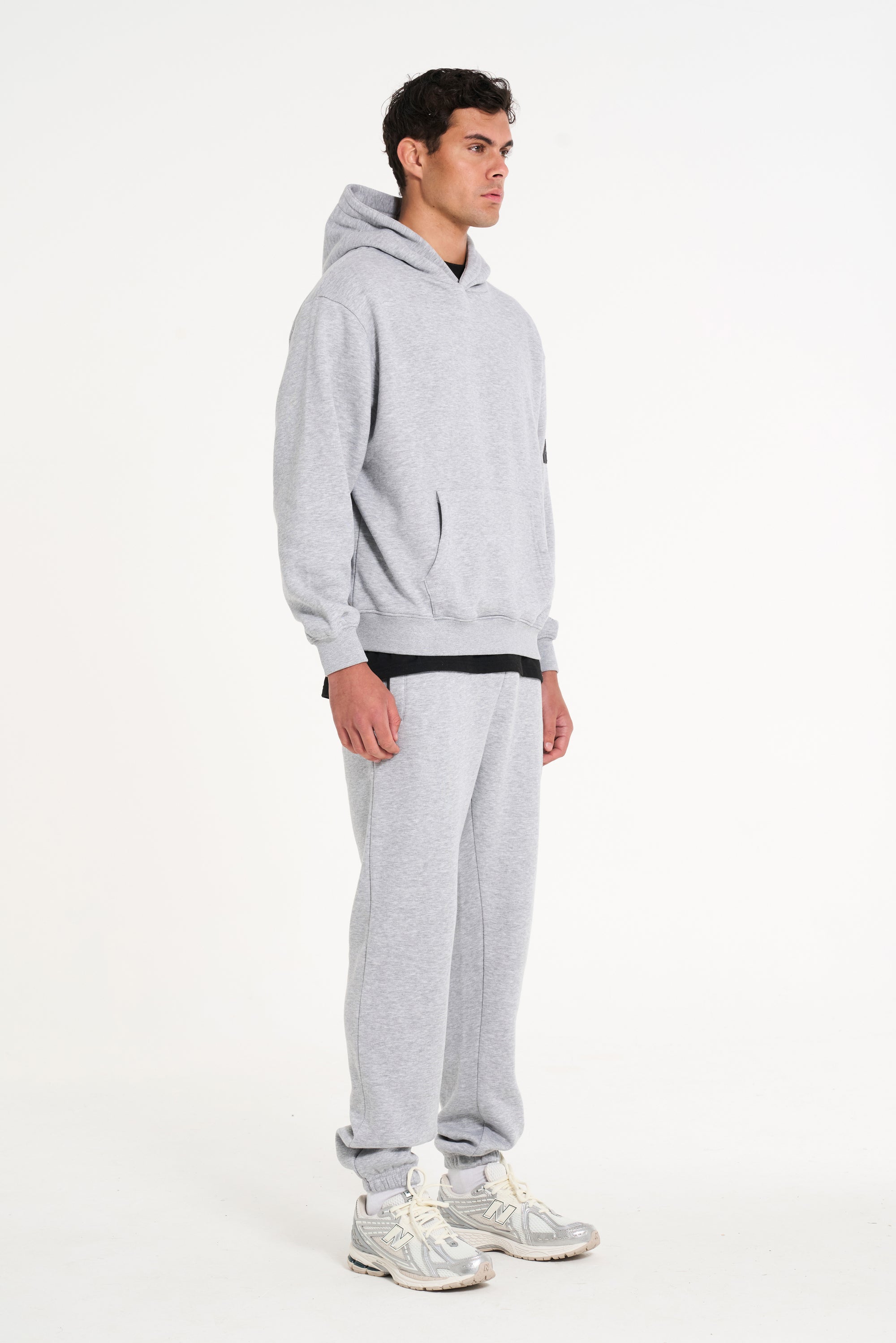 Model facing sidewards wearing full grey tracksuit