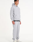 Model facing sidewards wearing full grey tracksuit