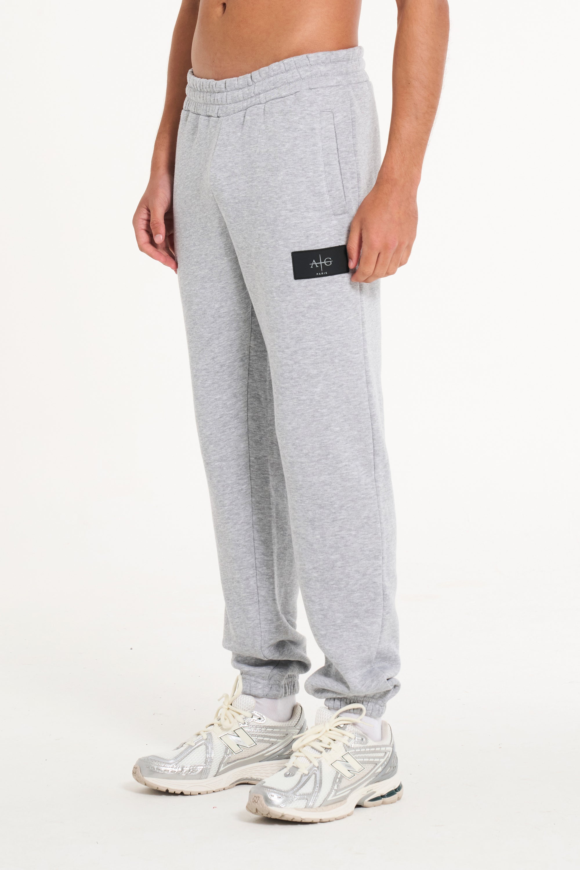 Side of men&#39;s tracksuit bottoms showing Avant Garde badge logo on upper leg