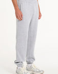 Model facing to the right showing bottom half of men's grey tracksuit