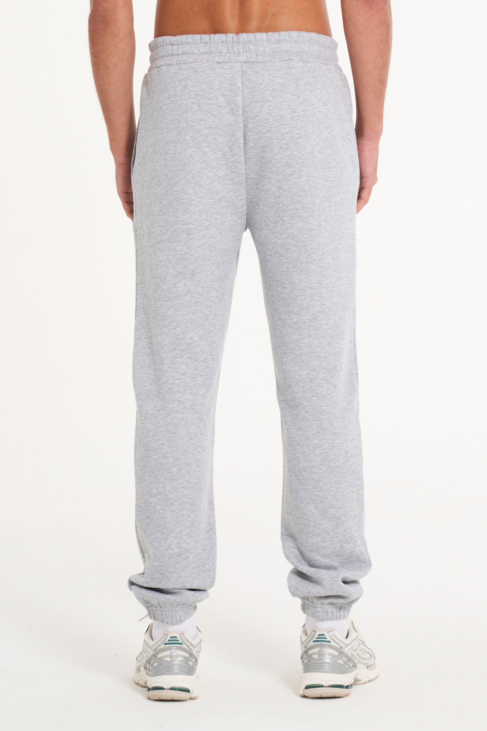 Bottom half of model wearing grey tracksuit bottoms facing away from camera