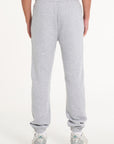 Bottom half of model wearing grey tracksuit bottoms facing away from camera