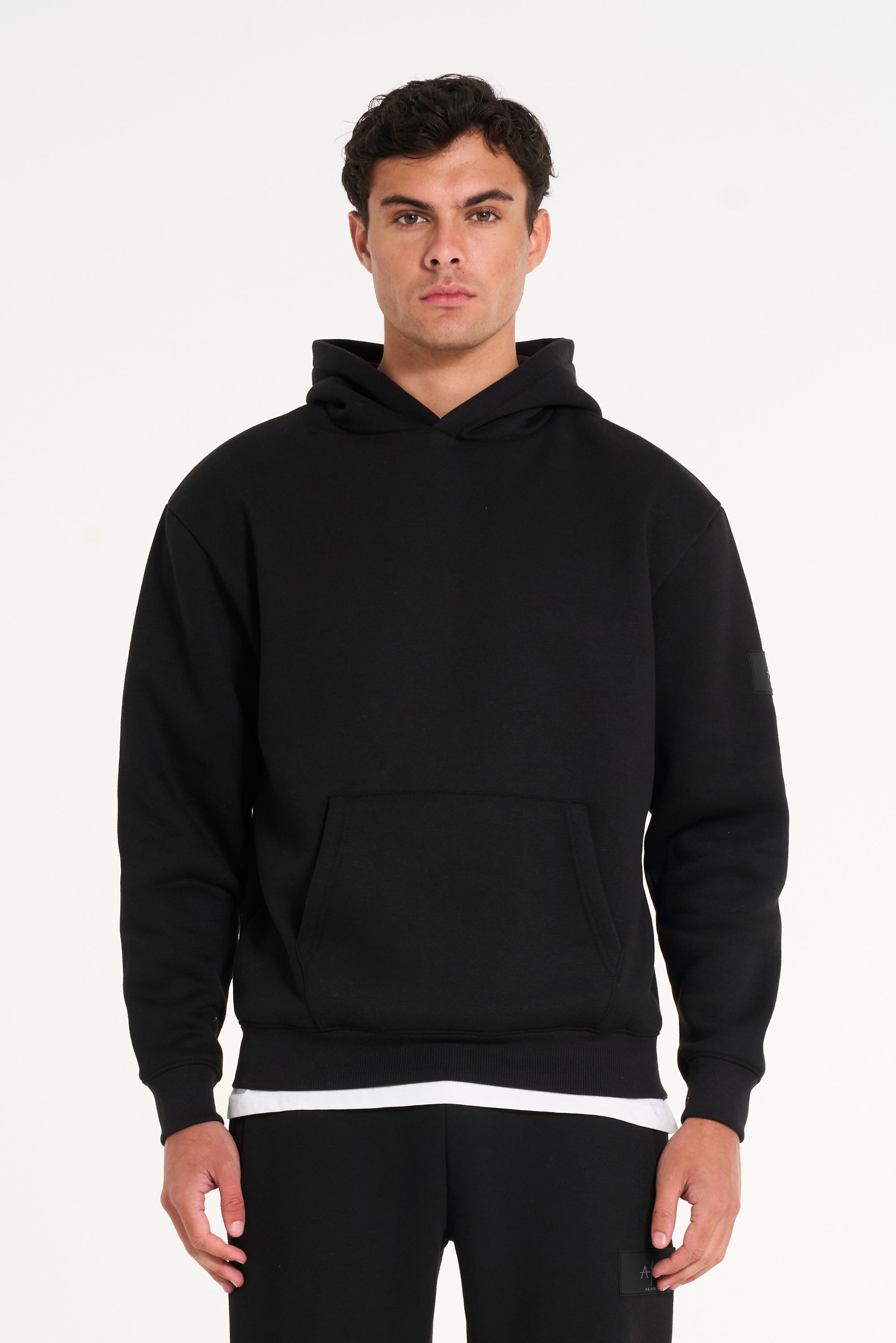 Close up frontshot of model wearing black tracksuit top with pocket