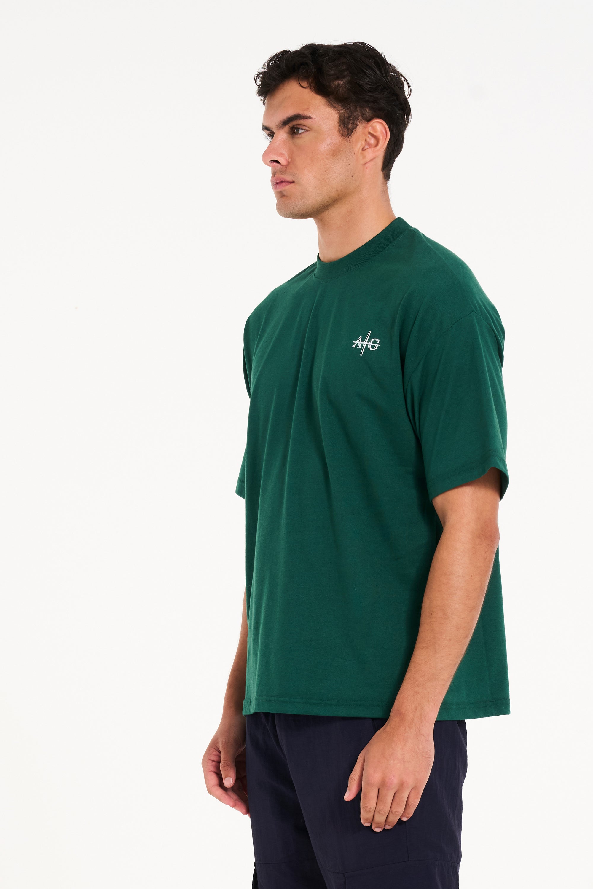 Model facing off to the left wearing green crew neck T-shirt