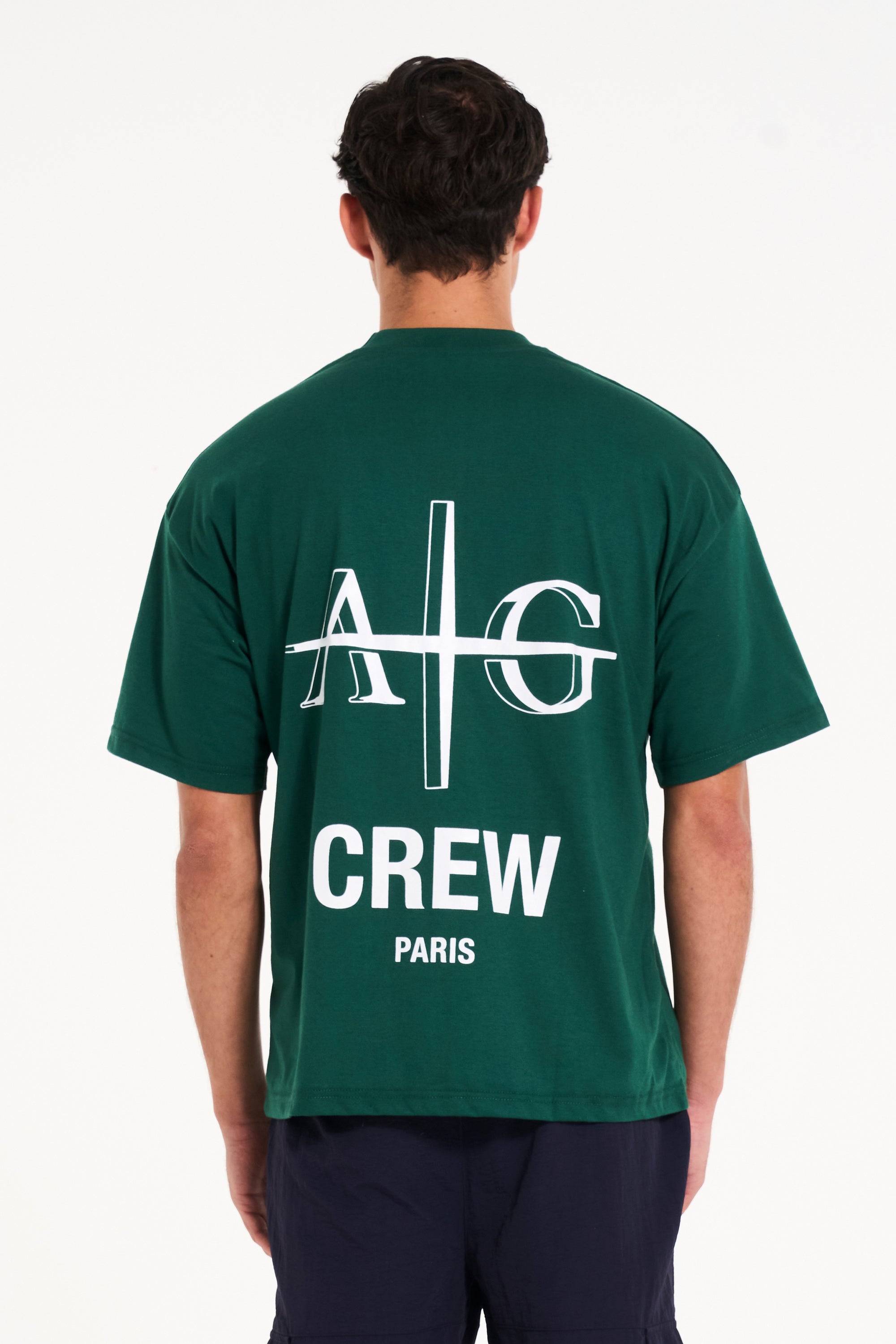 Backshot of model wearing green crew neck T-shirt showing large logo on the back