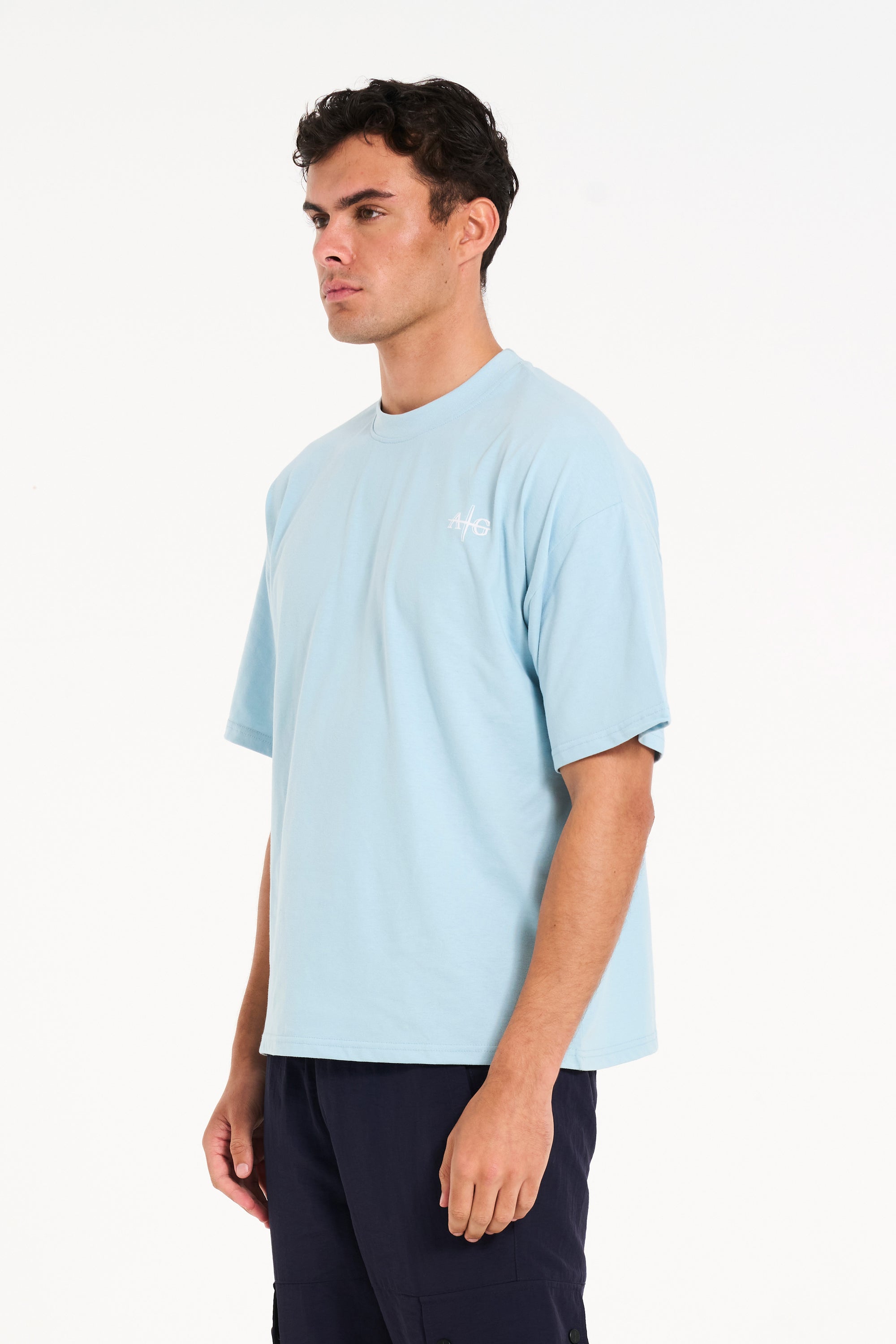 Close up shot of man facing to the side wearing sky blue crew neck T-shirt