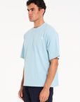 Close up shot of man facing to the side wearing sky blue crew neck T-shirt