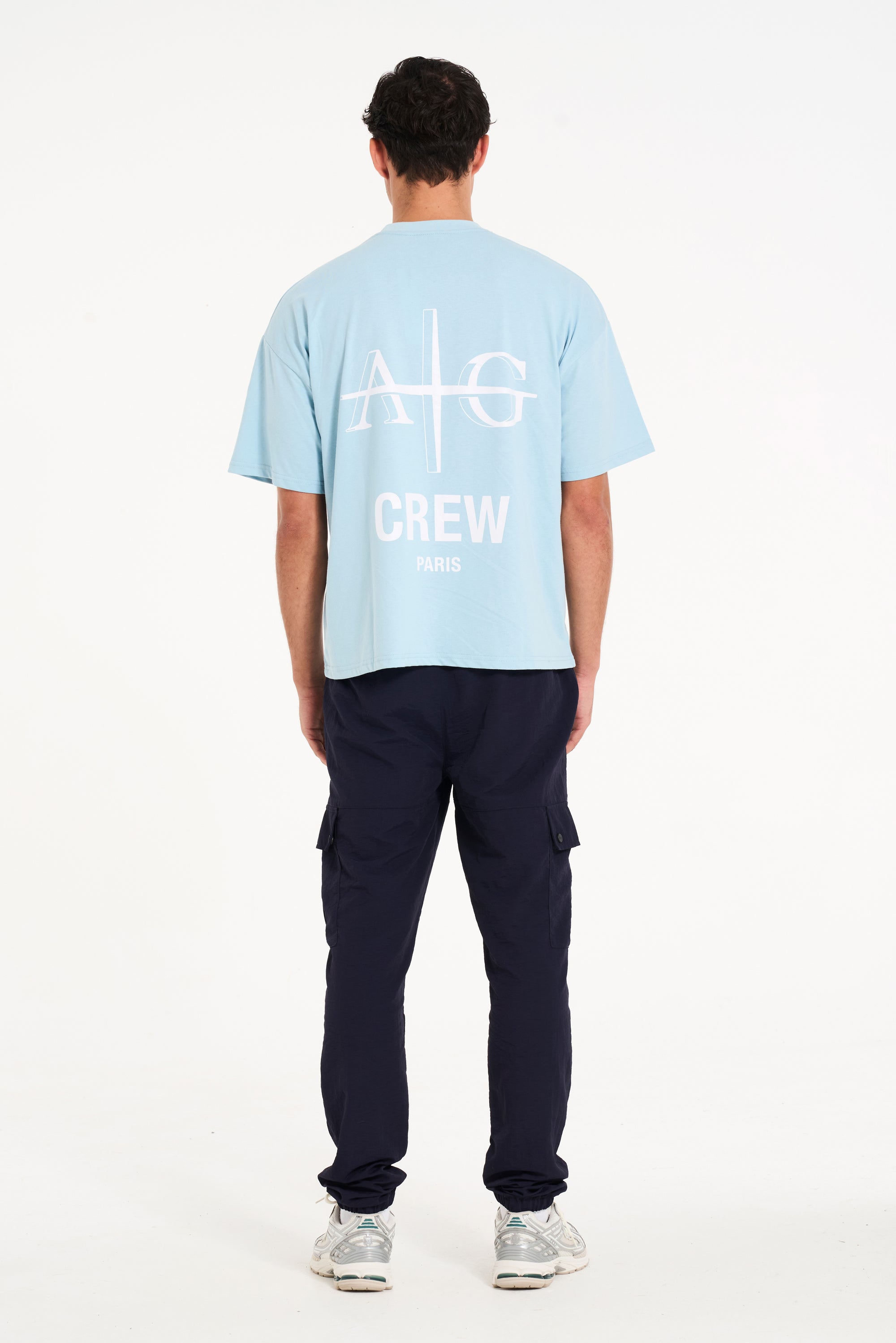 Backshot of man wearing sky blue T-shirt with large Avant Garde logo on the back