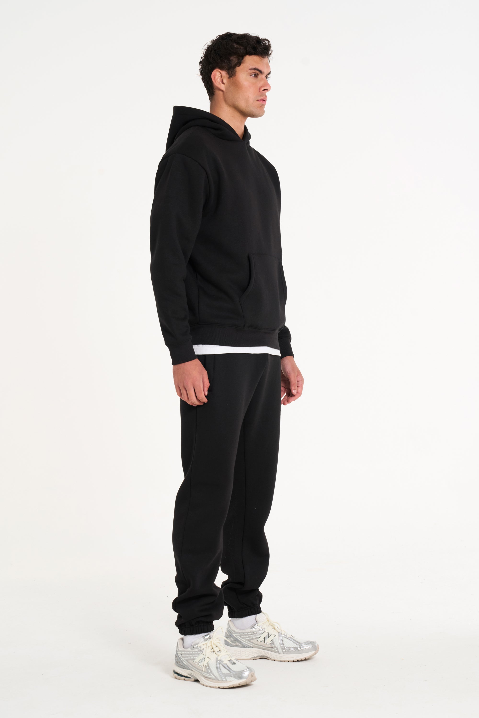 Model facing to the right wearing full tracksuit in black