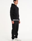 Model facing to the right wearing full tracksuit in black