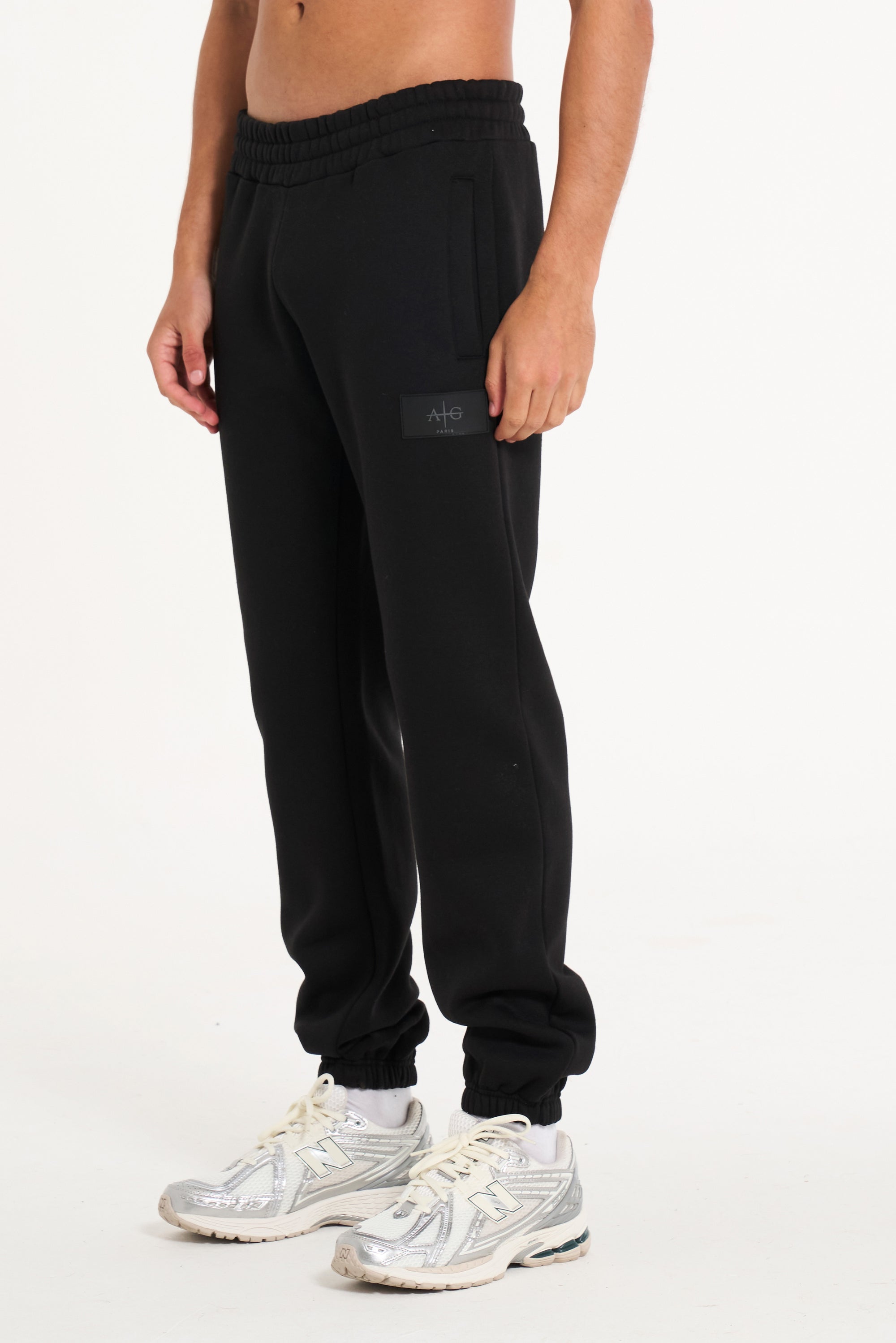 Close up shot of men&#39;s tracksuit bottoms in black with badge logo on the left leg