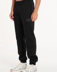 Close up shot of men's tracksuit bottoms in black with badge logo on the left leg